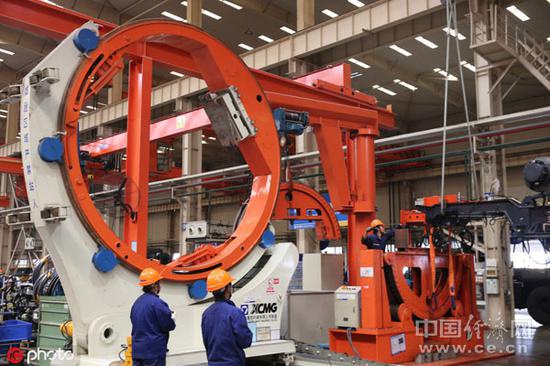  10月19日，徐工集团重型机械有限公司工作人员在装配分厂车间里组装工程机械。（图片来源：东方IC） 